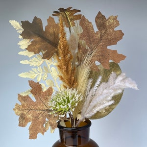 May include: A brown glass vase with a wide mouth filled with dried flowers and leaves in shades of brown, beige, and white.