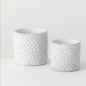 May include: Two white ceramic planters with a geometric diamond pattern. The planters are different sizes and are sitting on a white surface.