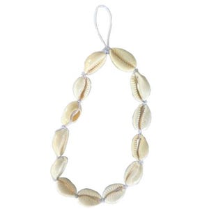 May include: A necklace made of cream-colored seashells strung together with white string. The shells are oval-shaped and have a natural, textured appearance. The necklace is designed to be worn around the neck.