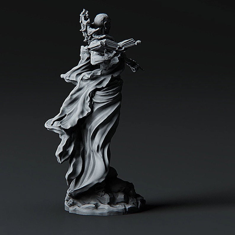 May include: A gray, sculpted figure of a person wearing a flowing robe. The figure is holding a staff in one hand and a book in the other. The figure is standing on a base.