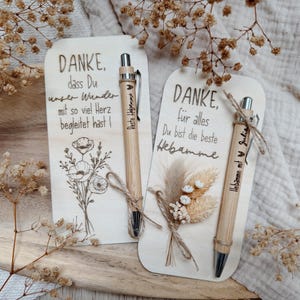 May include: Two wooden cards with German text and floral illustrations, accompanied by bamboo pens. One card says "DANKE" and the other says "DANKE, f&uuml;r alles". The pens have text and are tied with twine.