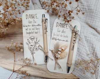 Puede incluir: Dos tarjetas de madera con texto en alemán e ilustraciones florales, acompañadas de bolígrafos de bambú. Una tarjeta dice "DANKE" y la otra dice "DANKE, für alles". Los bolígrafos tienen texto y están atados con hilo.