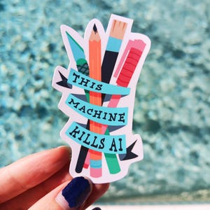 May include: A white sticker with a bunch of colorful pencils and pens, with the text "THIS MACHINE KILLS AI" on a blue banner.