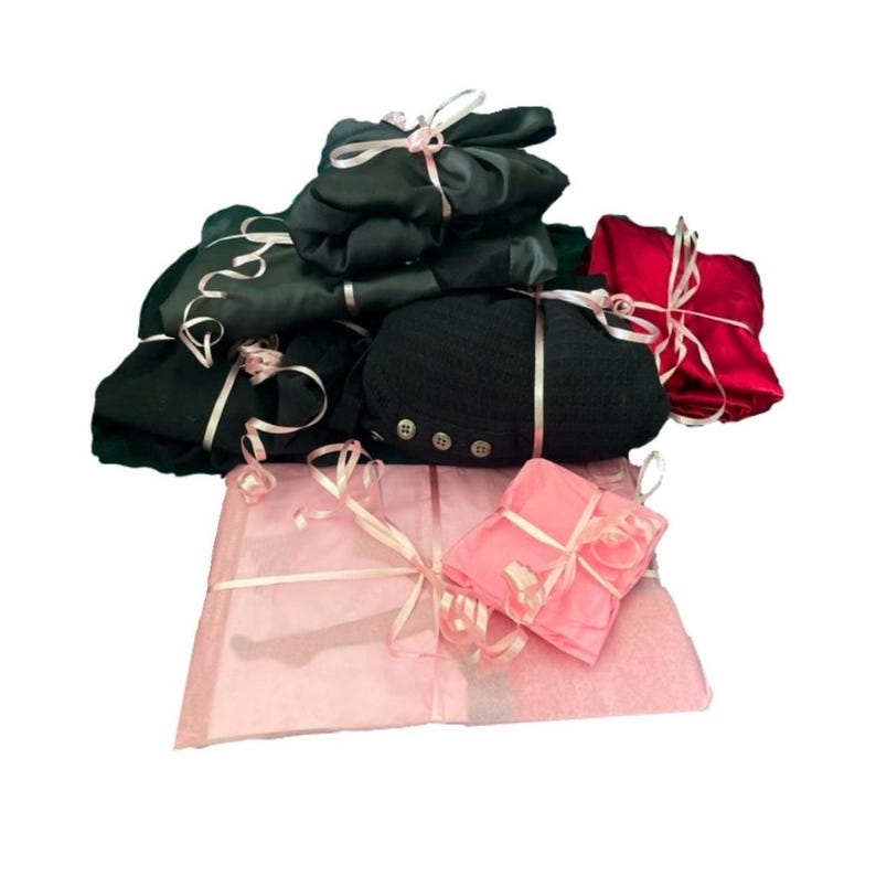 Pode incluir: Uma pilha de presentes embrulhados em papel de seda preto, vermelho e rosa com fita rosa. Os presentes est&atilde;o dispostos em forma de pir&acirc;mide.