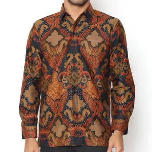 Op de afbeelding: Een overhemd met lange mouwen met een bruin, zwart en rood batikpatroon. Het overhemd heeft een knoopsluiting en een knoopsluiting.