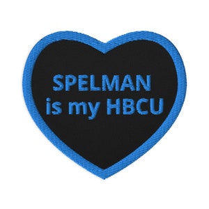 Könnte beinhalten: Schwarzer herzförmiger Patch mit blauem Rand. Der Text "SPELMAN is my HBCU" ist in Blau auf den Patch gestickt.