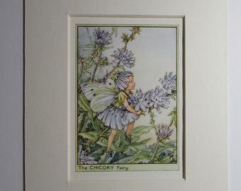 Könnte beinhalten: Ein gerahmter Druck mit einer Fee mit Schmetterlingsflügeln, die ein hellblaues Kleid trägt, inmitten blauer Blumen. Das Kunstwerk trägt den Titel "The CHICORY Fairy" und ist auf einem cremefarbenen Passepartout angebracht.