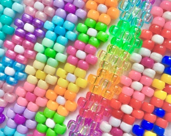 May include: A close-up of colorful plastic beads arranged in rows, forming a pattern of flowers. The beads are in various shades of pink, purple, blue, green, yellow, and orange.