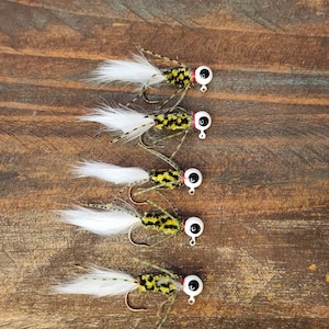 May include: Five white and yellow fishing lures with black eyes and white feathers.