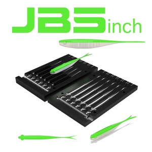 Puede incluir: Un molde de plástico negro con múltiples cavidades para hacer señuelos de pesca de plástico blando de 7,6 cm. El molde está abierto y muestra las cavidades. Hay cuatro señuelos de plástico blando verde y blanco junto al molde.