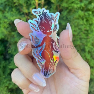 May include: A holographic sticker featuring a stylized illustration of a person with flames for hair. The person is standing with their arms outstretched and has a red, orange, and yellow color scheme.