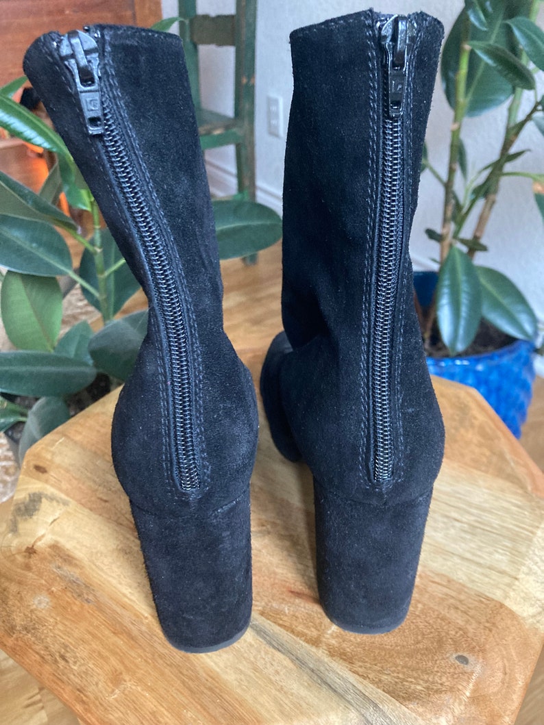 May include: A pair of black suede ankle boots with a zipper up the back. The boots have a block heel.