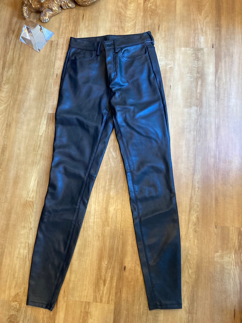 May include: Black leather pants with a slim fit and a zipper fly.
