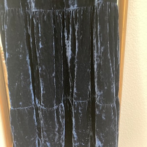 May include: A dark blue velvet dress with a tiered skirt. The dress has a crinkled texture and a loose fit.
