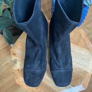 May include: A pair of black suede ankle boots with a pointed toe and a low heel.