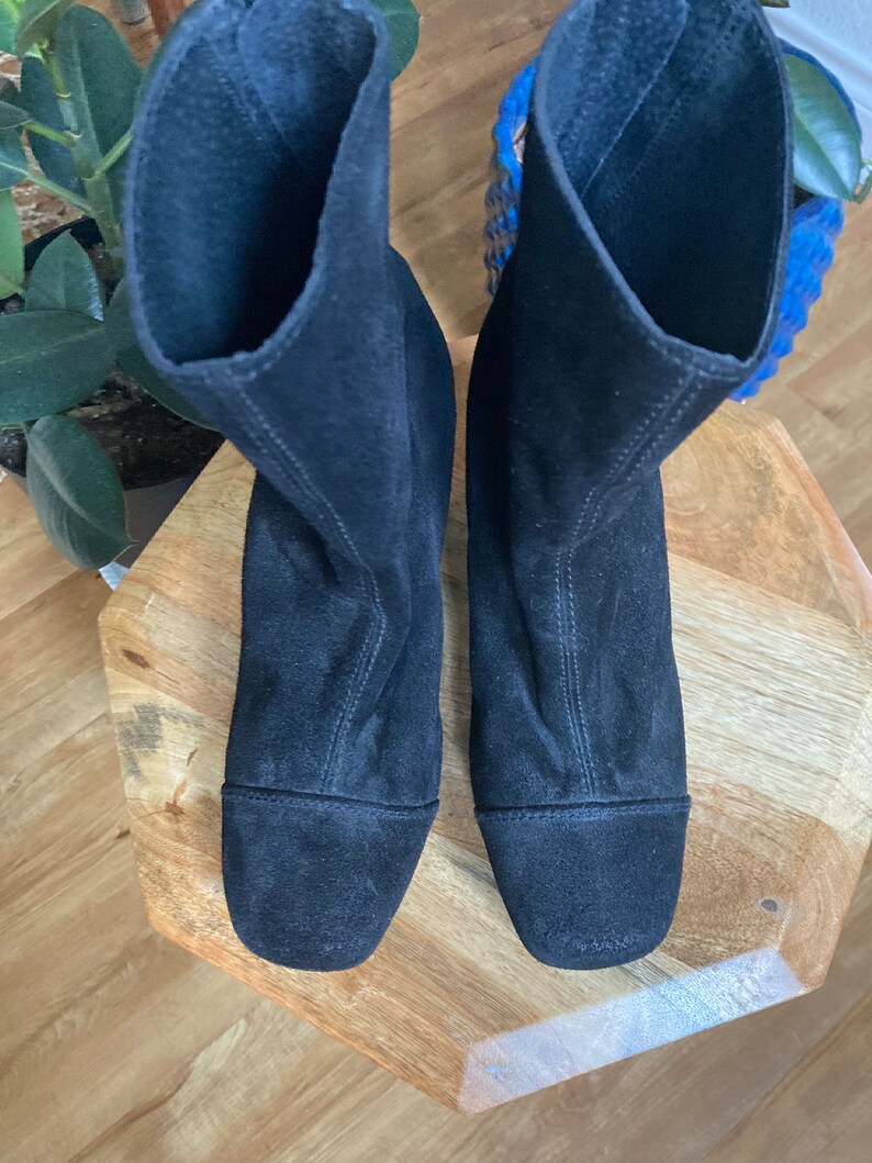 May include: A pair of black suede ankle boots with a pointed toe and a low heel.
