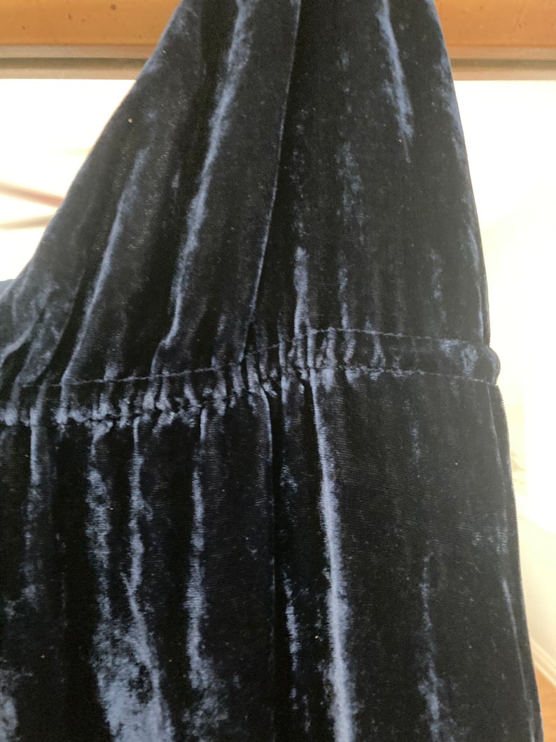 May include: Close-up of a dark blue velvet fabric with a gathered seam.