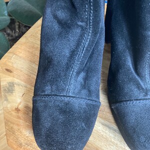 May include: A pair of black suede ankle boots with a square toe and a low block heel.