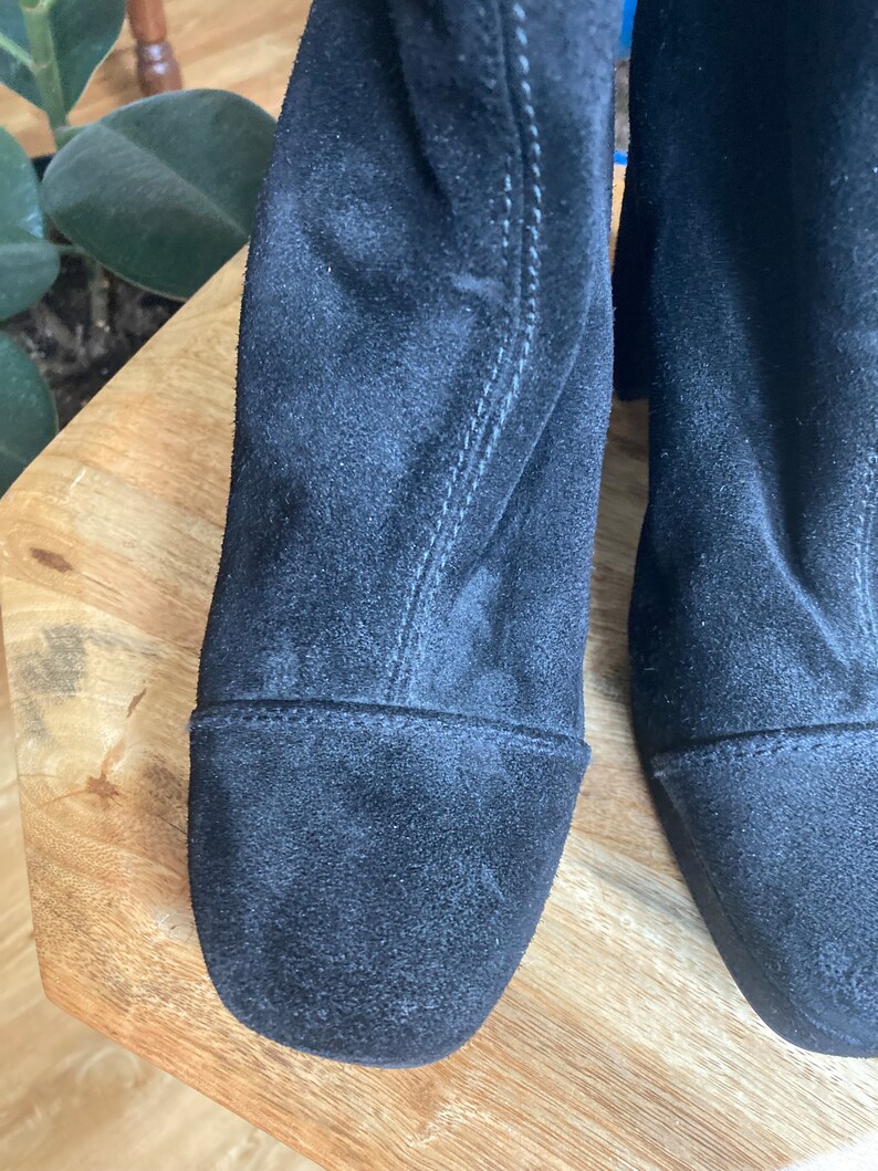 May include: A pair of black suede ankle boots with a square toe and a low block heel.