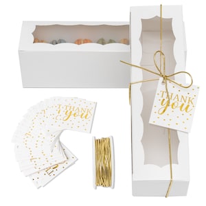May include: White gift boxes with clear windows, gold ribbon, and gold foil "Thank You" tags. The set includes a spool of gold ribbon and a stack of white gift tags with gold foil "Thank You" text and gold dots.