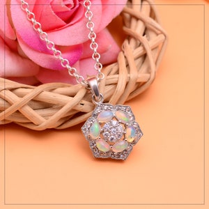 May include: A silver necklace with a flower-shaped pendant featuring white opals and clear cubic zirconia stones.