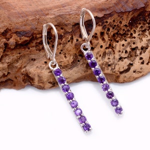May include: A pair of silver dangle earrings with a row of purple amethyst gemstones.