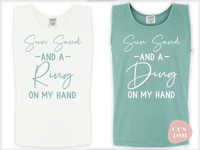 Op de afbeelding: Twee witte tanktops met een teal blauwe grafische afbeelding met de tekst "Sun Sand -AND A- Ring ON MY HAND" en "Sun Sand -AND A- Ding ON MY HAND".