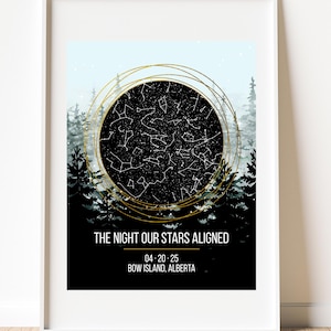 May include: Framed print with a star map design. The black and white star chart is encircled by gold lines, set against a forest and a light blue sky. Text reads "THE NIGHT OUR STARS ALIGNED" with a date and location.