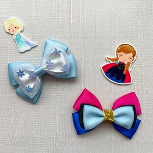 May include: Two hair bows with a blue and white snowflake design and a blue, pink, and black bow with gold glitter. The bows are on a white textured background with two cartoon images of the characters from the movie Frozen.