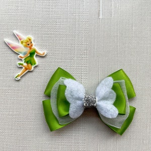 May include: Green and white bow with a sparkly center. The bow is made of satin ribbon and tulle.