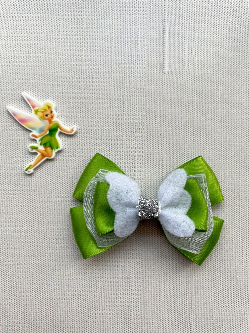 May include: Green and white bow with a sparkly center. The bow is made of satin ribbon and tulle.