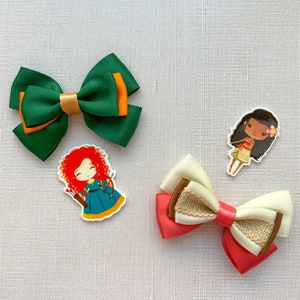 May include: Three hair bows with cartoon character embellishments. The bows are green, pink and white with brown accents. The characters are a girl with red hair, a girl with brown hair and a girl with black hair.