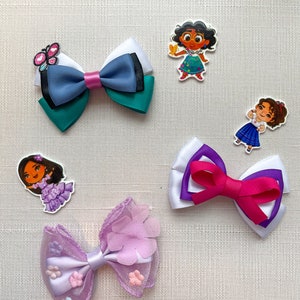 May include: Four handmade hair bows with different designs. The bows are made with satin ribbon, tulle, and lace. The bows are decorated with flowers, butterflies, and cartoon characters.