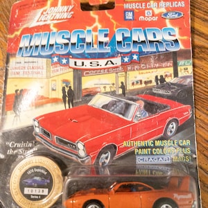 Peut inclure: Une réplique de voiture musculaire en métal moulé sous pression rouge, blanche et bleue d'une Plymouth Superbird de 1970. La voiture est sur une carte d'affichage avec les mots "Muscle Cars" et "Édition limitée" imprimés dessus. La voiture est 100% en métal moulé sous pression et présente des couleurs de peinture de voiture musculaire authentiques et des jantes Cragar.