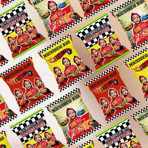 Könnte beinhalten: Ein Set mit 12 roten, gelben und schwarzen Party-Geschenktüten mit einem karierten Muster. Jede Tüte zeigt ein Foto eines Kindes in einem roten Rennanzug und den Text "Mackenzie Kiel 1. Geburtstag" oder "Fast One".