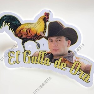 May include: A white sticker with a yellow rooster and a man wearing a cowboy hat. The text "El Gallo de Oro" is written in yellow letters.
