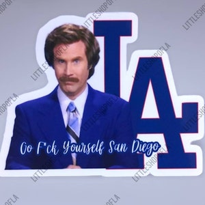 May include: A sticker featuring a man in a blue suit with a mustache, and the text "Go F*ck Yourself San Diego." The background includes the Los Angeles Dodgers logo in blue and white.