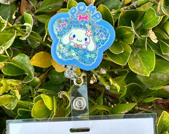 May include: A blue and white glitter badge holder with a cartoon dog and the word "Pomp" on it. The badge holder is attached to a clear plastic badge holder.