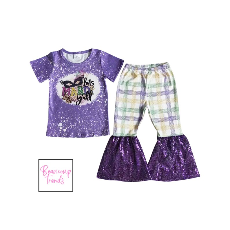 May include: A purple two-piece outfit featuring a short-sleeved t-shirt and flared pants. The shirt has a graphic that says "Lets Mardi Yall" with a mask design. The pants have a plaid pattern with sequined purple flares.