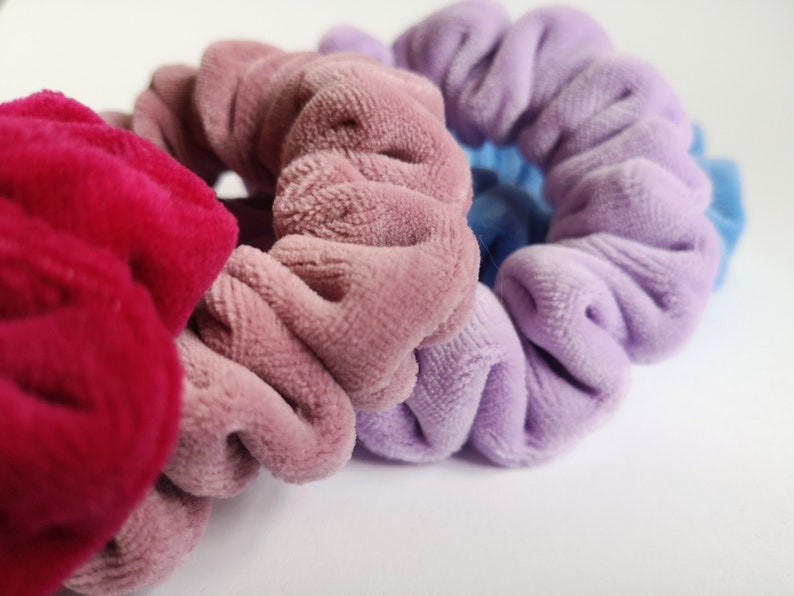 Pu&ograve; includere: Tre scrunchies di diversi colori: rosa, viola e rosso. Gli scrunchies sono realizzati in tessuto morbido e peloso.