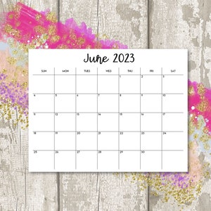 Puede incluir: Un calendario blanco para junio de 2023, con un dise&ntilde;o de cuadr&iacute;cula simple. El calendario est&aacute; sobre un fondo de madera gris claro desgastado, acentuado con vibrantes pinceladas rosas y doradas.