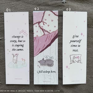 May include: Three pink and white bookmarks with illustrations of cats and inspirational quotes. The first bookmark says "change is scary, but so is staying the same." The second bookmark says "i fell asleep here." The third bookmark says "give yourself time to rest."