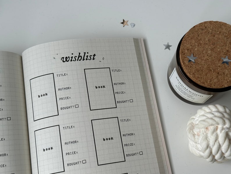 Puede incluir: Una p&aacute;gina de un cuaderno con un patr&oacute;n de cuadr&iacute;cula, titulada "wishlist". La p&aacute;gina est&aacute; dividida en cuatro secciones, cada una con un encabezado para "book" y espacios para escribir el t&iacute;tulo, el autor, el precio y si el libro se ha comprado.