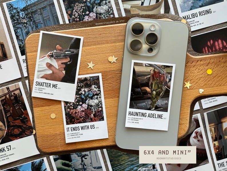 Pu&ograve; includere: Un set di sei stampe fotografiche da 15x10 cm con bordi bianchi e testo nero. Le stampe presentano i titoli di libri e film popolari, tra cui "Shatter Me", "It Ends With Us", "Haunting Adeline" e "Malibu Rising". Le stampe sono esposte su una superficie in legno con una custodia per smartphone e altri oggetti decorativi.