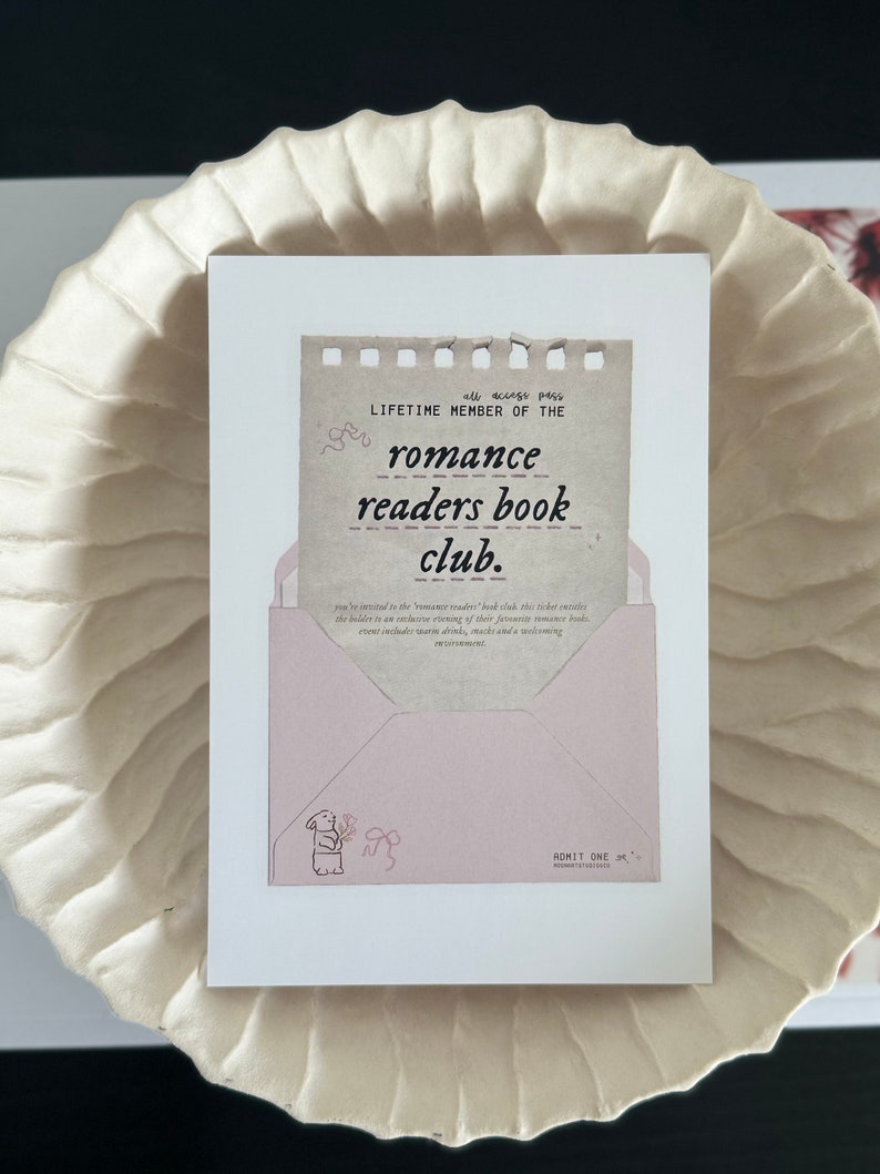 May include: A pink and brown card with the text "all access pass LIFETIME MEMBER OF THE romance readers book club." The card is folded into an envelope with a small illustration of a bunny holding flowers. The envelope has the text "ADMIT ONE" on the bottom.