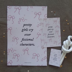 May include: Two pink and white printable art prints with the text "pretty girls cry over fictional characters." The prints feature a pattern of pink bows.