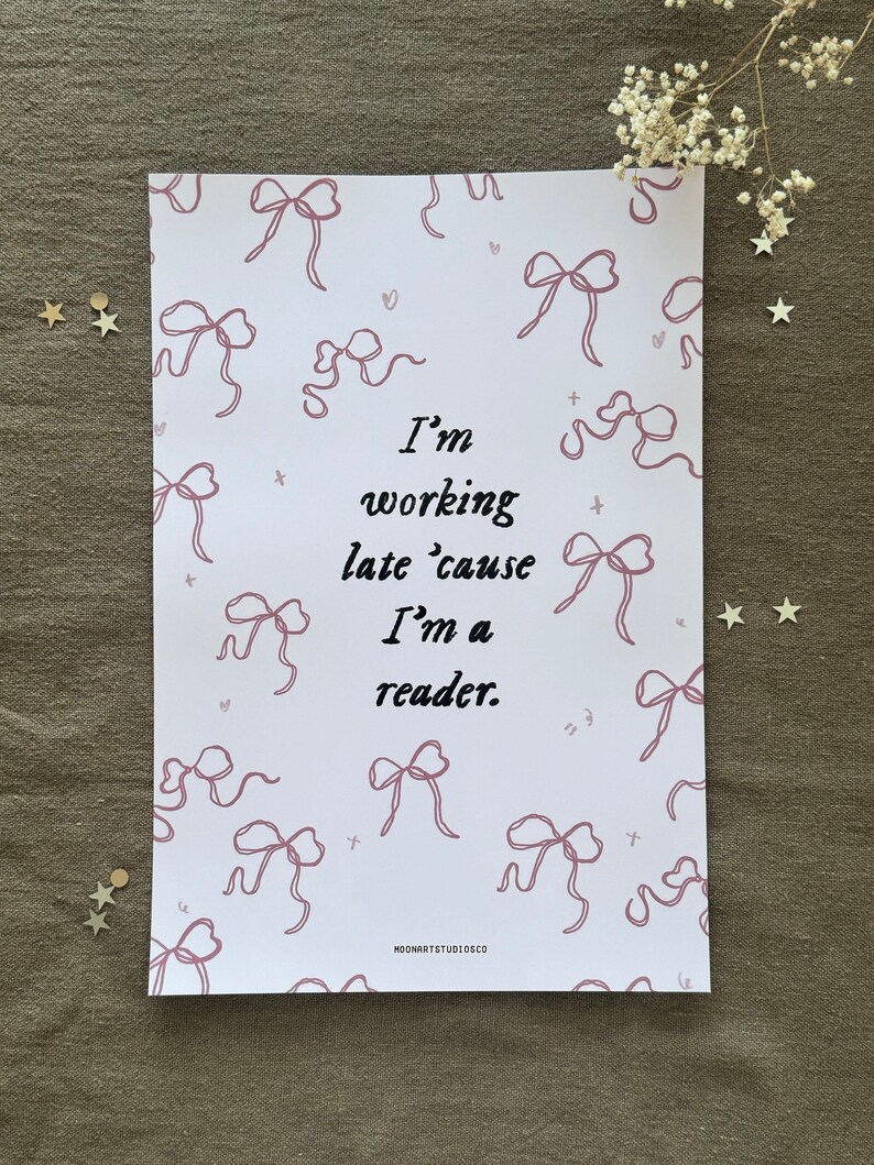 Op de afbeelding: Een witte printbare poster met een roze strikpatroon en de tekst "Ik werk laat omdat ik een lezer ben."