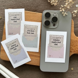 May include: Four white cards with a decorative envelope design and text that reads "cozy readers book club", "fantasy readers book club", "slow burn book club", and "romance readers book club".