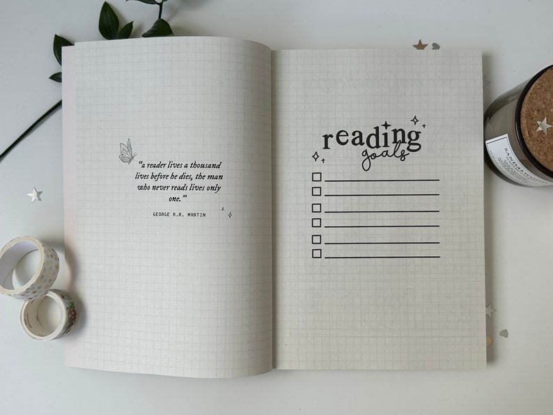 Puede incluir: Un cuaderno blanco cuadriculado con una cita sobre la lectura de George R.R. Martin en la p&aacute;gina izquierda y una lista de verificaci&oacute;n titulada "metas de lectura" en la p&aacute;gina derecha.