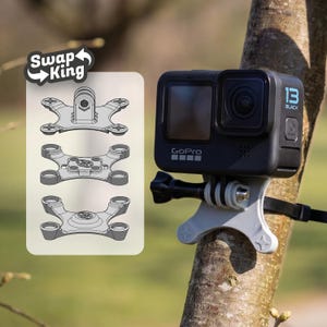 Może przedstawiać: Czarna kamera GoPro zamontowana na gałęzi drzewa z szarą konsolą. Kamera jest oznaczona jako "13 Black" i "GoPro". Schemat wymiennych mocowań jest pokazany z tekstem "Swap King".